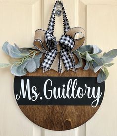 a wooden sign that says ms gullify hanging on a door with eucalyptus leaves