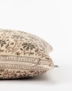 a pillow that is sitting on top of a white surface with brown and tan designs