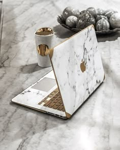 an open laptop computer sitting on top of a marble table next to silver balls and ornaments