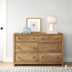 a wooden dresser sitting next to a white door in a room with a blue and white rug on the floor