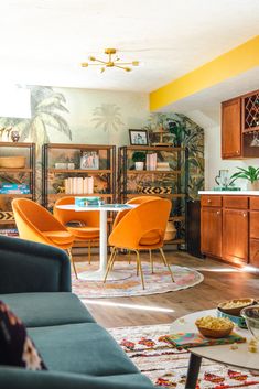 a living room filled with furniture next to a table and bookshelf on top of a hard wood floor