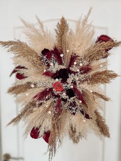 dried flowers and feathers are arranged in a star shape on a door hanger ornament