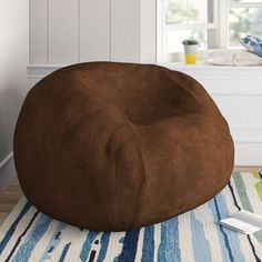 a brown bean bag chair sitting on top of a blue and white rug in front of a window