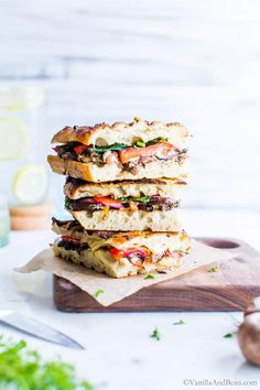 a stack of sandwiches sitting on top of a wooden cutting board next to a knife