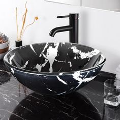 a black and white bowl sink sitting on top of a bathroom counter next to a faucet