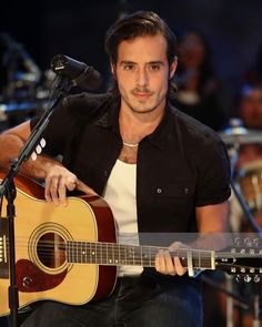 a man sitting in front of a microphone holding a guitar