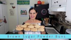 a woman holding a tray full of cookies in her kitchen with the words brown sugar powder buns