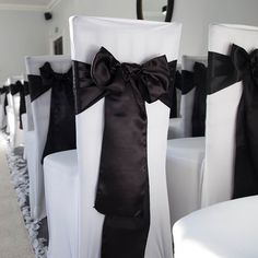 white chairs with black sashes and bows are lined up on the carpeted floor