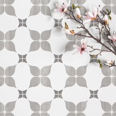 a branch with pink flowers on a gray and white wallpaper design pattern that looks like an ornament