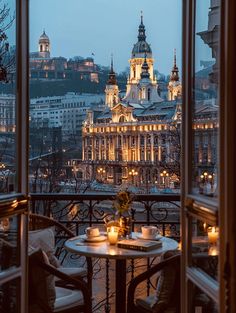 a table with two candles on it in front of a window overlooking a city at night