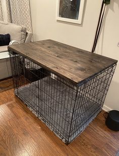 a dog cage sitting on top of a hard wood floor in a living room next to a couch