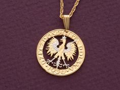 a gold necklace with an eagle on the front and two words written in white ink