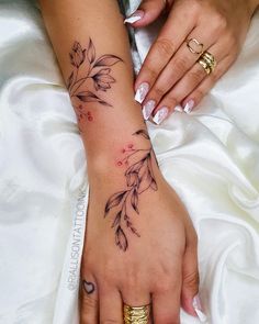 a woman's hand with tattoos on it and two gold rings around her wrist