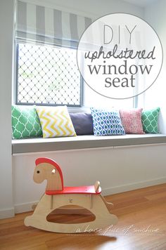 a wooden rocking horse in front of a window seat with pillows on the windowsill