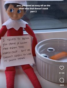 an elf holding a sign sitting on top of a sink