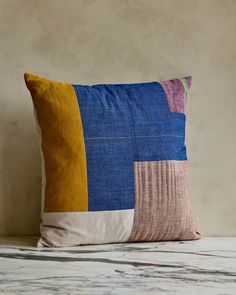 a blue and yellow pillow sitting on top of a white table next to a wall