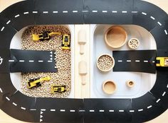 a toy car track with construction vehicles and gravel in the middle on top of it