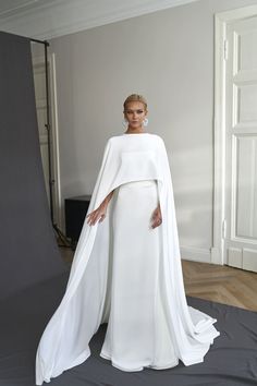 a woman in a white gown and cape