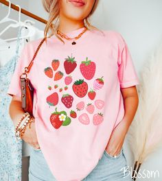 a woman wearing a pink shirt with strawberries on it