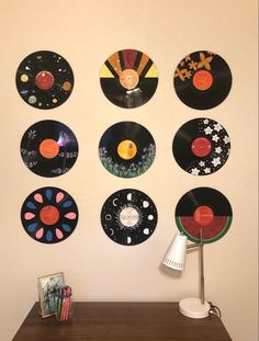 there are many records hanging on the wall next to a desk with a lamp and cd's