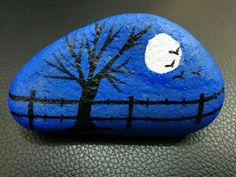 a painted rock with a tree and moon on it