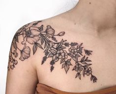 a woman's shoulder with flowers and leaves on her left arm, which is covered in black ink