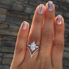 a woman's hand with a diamond ring on top of her finger and an engagement ring