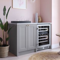 a wine cooler in the corner of a room next to a table and potted plant