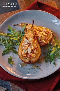 two pieces of food on a white plate with green garnish and almonds