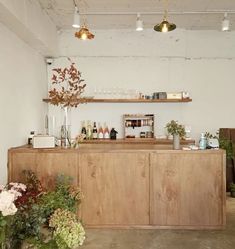 a wooden counter sitting in the middle of a room with lots of plants and bottles on it