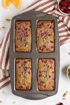 four cranberry orange muffins sitting in a pan on top of a table