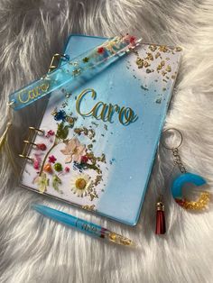 a blue notebook with the word care written on it next to two pens and a keychain