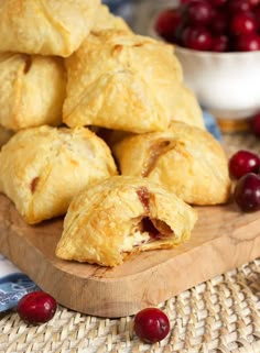 cranberry turnovers on a wooden cutting board with cherries in the background