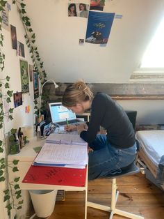 a woman sitting at a desk with a laptop computer and papers on top of it