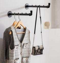 two purses hanging from hooks on a coat rack