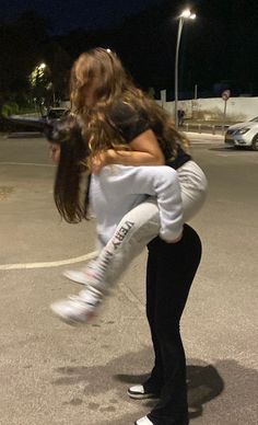 a woman is holding a child in the middle of an empty parking lot at night