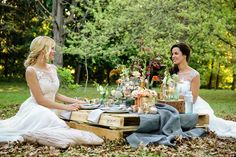 two women sitting at a table in the woods