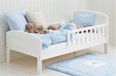 a child's bed with blue sheets and pillows on it, next to a teddy bear