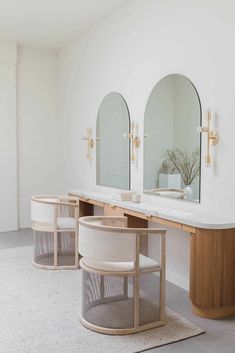 a bathroom with three mirrors and two stools