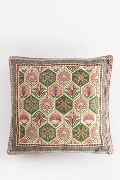 a decorative pillow with an embroidered design on the front and back, sitting against a white wall