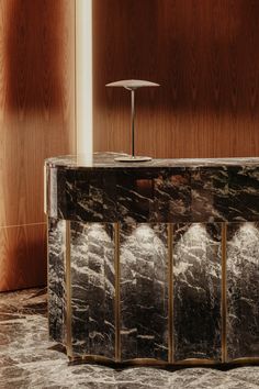 a marble counter in front of wooden paneled walls with a lamp on the top