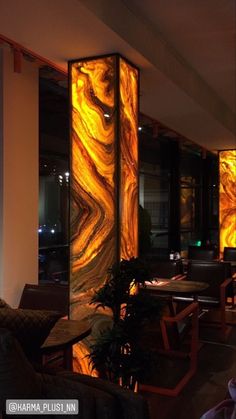 a room filled with lots of furniture next to a tall glass wall covered in yellow and orange swirls