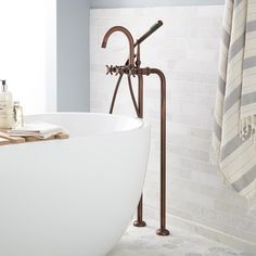 a bathtub with two faucets and towels hanging on the wall next to it