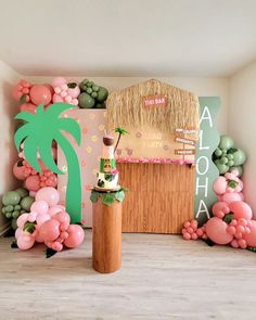 a party setup with balloons, palm tree and tiki hut on the wall behind it