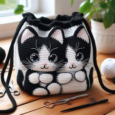 a crocheted purse with two black and white cats sitting on it's side