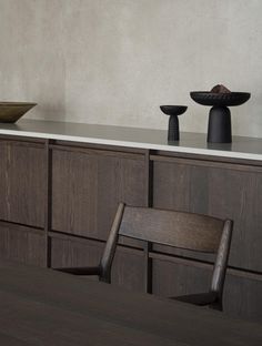 a wooden table topped with two black vases on top of it next to a counter