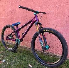 a purple bike leaning against a pink wall