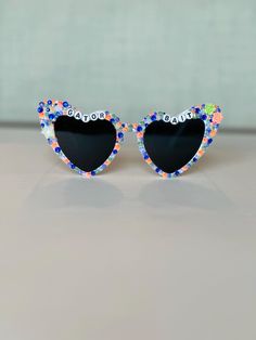 Bedazzled retro heart sunglasses perfect for any University of Florida fan.  Use these sunglasses to complete your Game Day outfit or gift to any Florida Gator! Please note this is a made to order item and no two sunglasses will be the same.  Exact color and placement of gems will have slight variation. Ensuring your purchases arrive in perfect condition is important to me! Sunglasses are packaged in hard, sturdy boxes with crinkle cut packing paper. All sunnies are shipped with a squeeze top soft leather case and cleaning cloth. I am happy to provide custom orders! Please message me if you would like different color rhinestones, sunglasses, color of letters, or word combo than displayed.  I am happy to answer any questions. Returns or exchanges are not accepted due to the custom nature of Heart-shaped Glass Sunglasses For Gift, Heart-shaped Glass Sunglasses As Gift, Retro Sunglasses With Tinted Lenses As Gift, Retro Sunglasses With Tinted Lenses For Gift, Retro Sunglasses With Tinted Lenses As A Gift, Heart-shaped Sunglasses With Uv Protection As Gift, Heart-shaped Sunglasses With Tinted Lenses As Gift, Heart-shaped Sunglasses With Tinted Lenses For Gift, Cute Glass Sunglasses For Gift