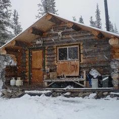 a cabin in the woods with snow falling on it's roof and trees around