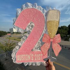 someone holding up a sign with two champagne glasses on it